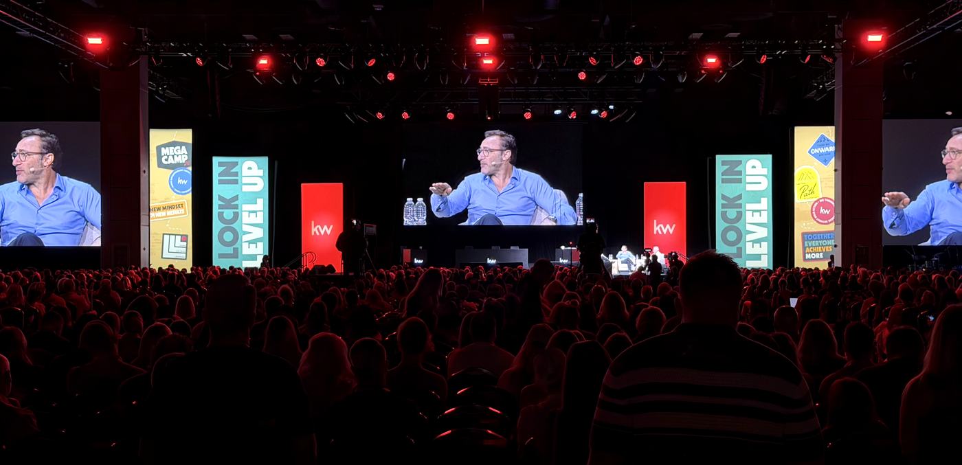 Wide view of the Mega Camp 2026 main stage with Simon Sinek on the screens and a full room of agents